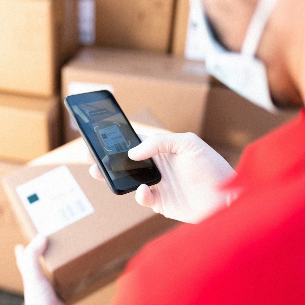 Man holds smart phone in hand with camera on and scans barcode on box