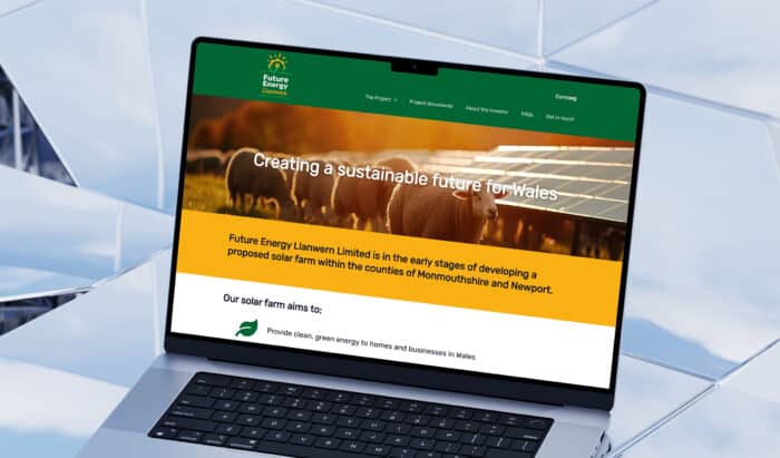 Laptop screen showing the 'Future Energy Llanwern' website homepage with a banner image of sheep grazing near solar panels and text promoting a sustainable future for Wales.